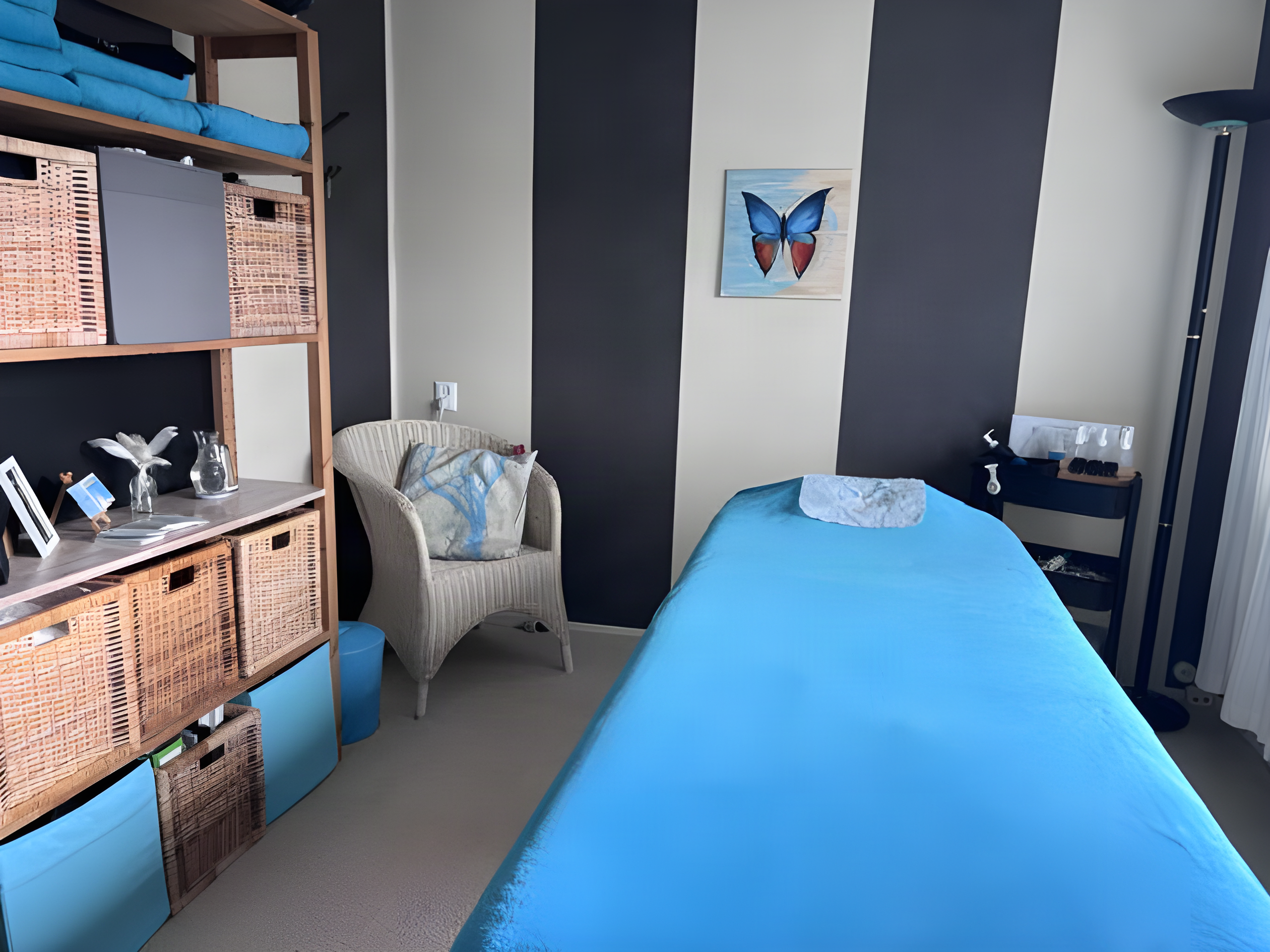 De praktijkruimte met massagetafel en vlinderschilderij
